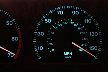 speedometer in car dashboard at full speed in illuminated night mode