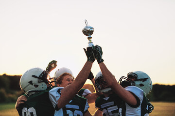 Cheering football team holding up a trophy