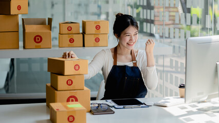 A beautiful Asian business owner opens an online store, she is checking orders from customers,...