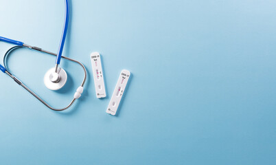 Covid-19 rapid antigen test and stethoscope on blue background. Worldwide coronavirus epidemic...