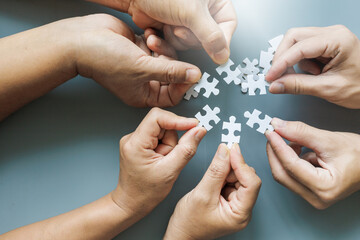 Close up Businesspeople hand holding jigsaw puzzle on gray background, success and strategy concept.