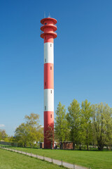 Vertical shot of red white lighthouse against blue sky at the North Sea coast in East Frisia, Germany.