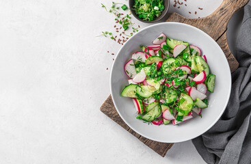 Summer vegetable salad with radish, cucumber and herbs on a gray background. Healthy, dietary salad. Top view, space to copy.