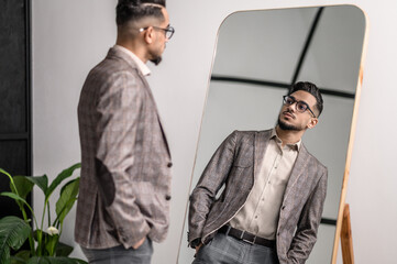 A good-looking young stylish man at the mirror