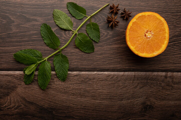 Orange, star anise and mint on a dark wood background with copy space