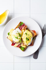 Eggs benedict on crispy toast with bacon and traditional hollandaise sauce. Delicious breakfast concept.