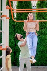 Fototapeta premium A family having fun at the sports gound on horizontal bar