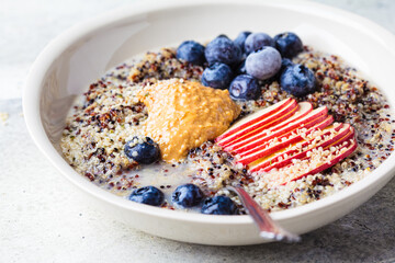 Quinoa porridge with apple, blueberry, peanut butter and hemp seeds for breakfast. Vegan food...