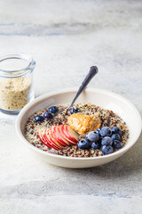 Quinoa porridge with apple, blueberry, peanut butter and hemp seeds for breakfast. Vegan food concept.