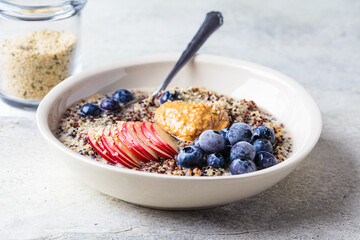 Quinoa porridge with apple, blueberry, peanut butter and hemp seeds for breakfast. Vegan food concept.