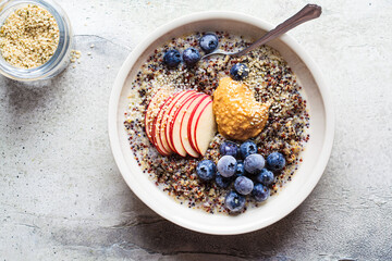 Quinoa porridge with apple, blueberry, peanut butter and hemp seeds for breakfast. Vegan food concept. - obrazy, fototapety, plakaty