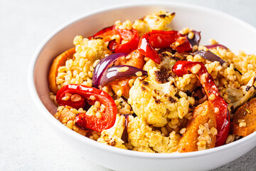Roasted vegetables salad with bulgur in white bowl. Vegan food concept.