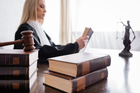 collection of books and gavel near prosecutor reading on blurred background.