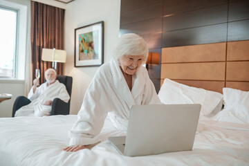 Elderly woman in a hotel room with a laptop
