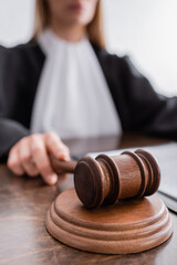 close up view of wooden gavel in hand of cropped judge on blurred background.