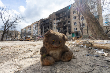 Concept war in Ukraine, a burnt bear toy against the background of a damaged house