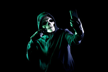 Obraz na płótnie Canvas Modern death character on a black background taking a selfie with his phone
