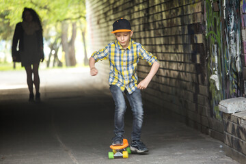 A boy rides a skateboard through an underpass in the city. A child plays outdoor games in the spring
