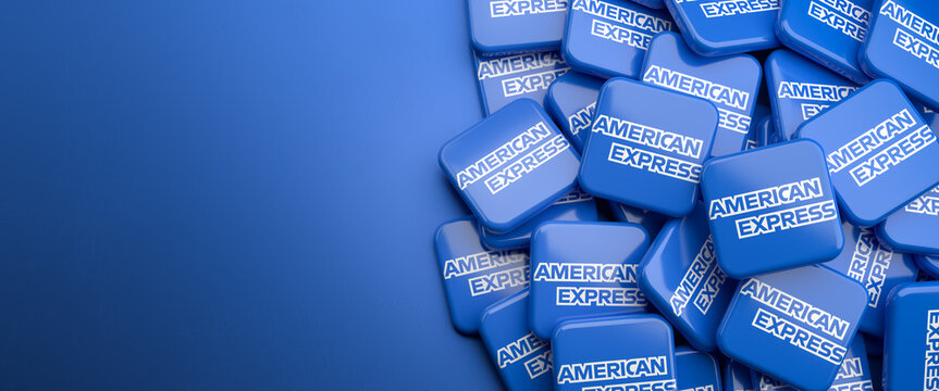 Logos of the payment card services company American Express on a heap on a table. Copy space. Web banner format.
