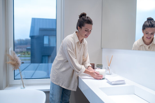 A Young Woman Putting Air Freshener In The Bathroom