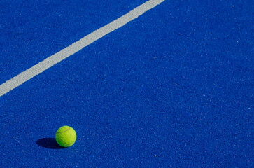 Isolated ball on a blue paddle tennis court, racket sports concept