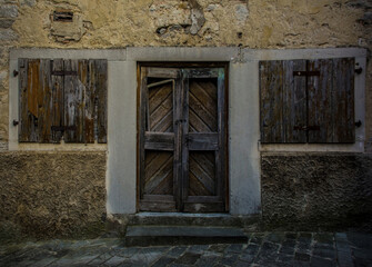 An old wooden door and windows in an historic derelict residential building in the medieval village...