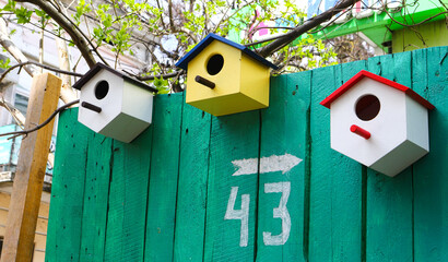 Multicolored birdhouses. Decorative Colored Colorful houses for birds. Bird houses on the fence and wall.