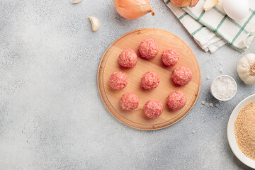 Top view of raw meat balls on a wooden board