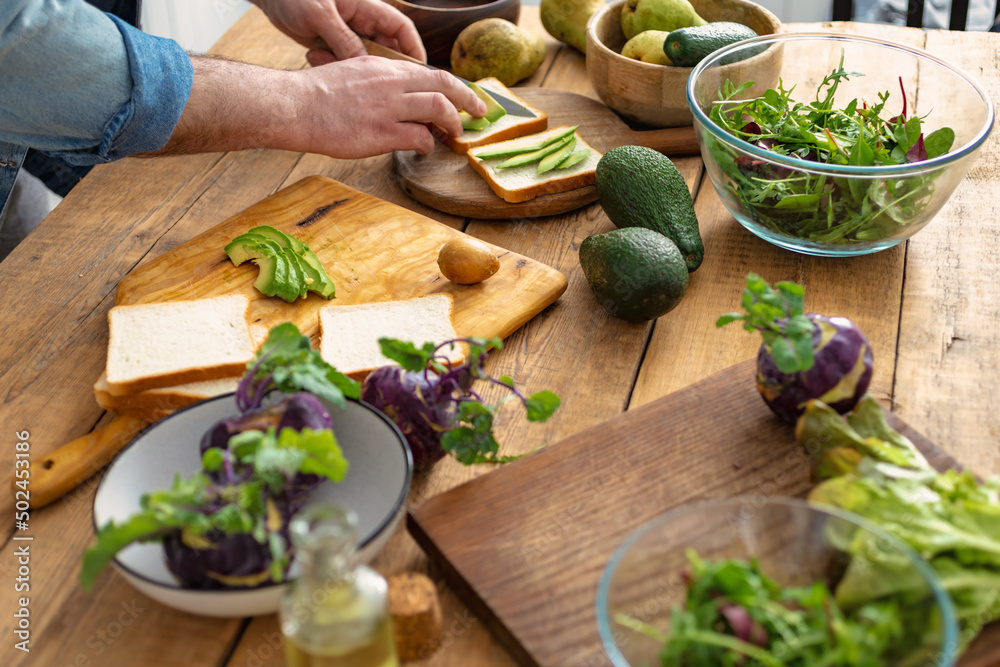 Canvas Prints man preparing avocado sandwiches at home kitchen. cooking a healthy and tasty breakfast or lunch