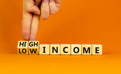 Low or high income symbol. Businessman turns wooden cubes and changes words Low income to High income. Beautiful orange table orange background, copy space. Business low or high income concept.