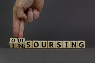 Outsourcing or insourcing symbol. Businessman turns wooden cubes and changes the word Outsourcing...