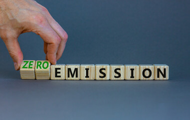 Zero emission symbol. Businessman turns wooden cubes and changes words Emission to Zero emission. Beautiful grey background. Business, ecological and zero emission concept. Copy space.