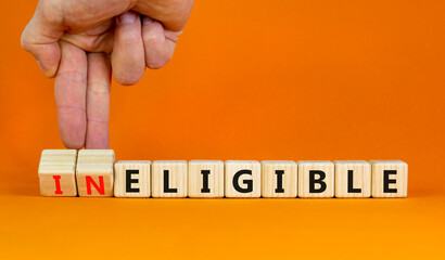 Eligible or ineligible symbol. Businessman turns wooden cubes and changes words Ineligible to Eligible. Beautiful orange table orange background. Business eligible or ineligible concept. Copy space.