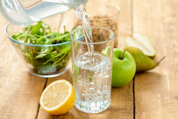 Healthy breakfast. Food set for diet and healthy food. Clean fresh water is poured into a glass beaker while standing on a wooden table with fruits, granola and salad bowl on wooden table