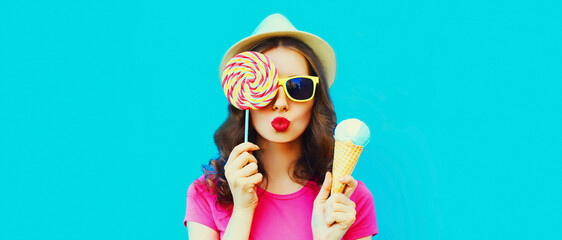 Portrait of happy young woman with ice cream blowing her lips on blue background