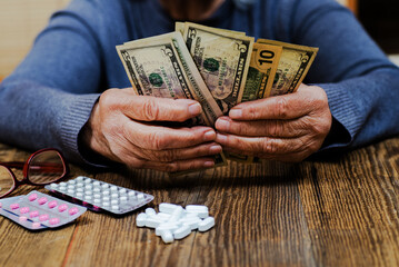 Hands of an old woman near money and medicines.  Medicines and money in the hands of  pensioner.