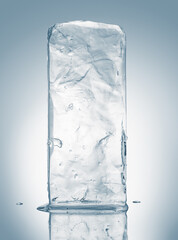 Crystal clear natural ice block in light blue tones on a white reflective surface.