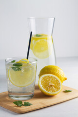 glass of lemonade.Summer refreshing cocktail with lime and mint on white wooden background. Fresh summertime iced drink with yellow citrus and green leaves in glasses on cutting board. vertical