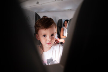 A little boy looking at the camera on a plane