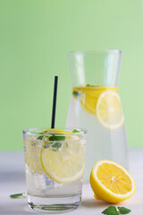 glass of lemonade.Summer refreshing cocktail with lime and mint on white and green background. Fresh summertime iced drink with yellow citrus and green leaves in glasses. copy space. vertical