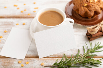 White paper business card mockup with cup of coffee and cake on white wooden background. side view