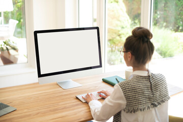 Rear view shot of businesswoman sitting in front of blanc screen computer while typing on the...