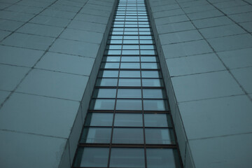 Fototapeta na wymiar High-rise building on gray day. Architecture details. Surface of wall.