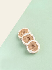 Peat briquettes for growing seedlings and young plants on a green and beige background. isometric