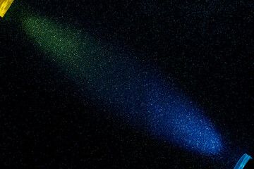 On a dark blue background, light green and light blue rays of light have merged into small...