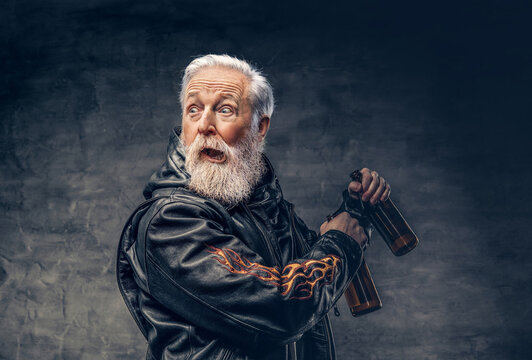 Studio shot of shocked grandfather motorcyclist with two bottles dressed in leather jacket.