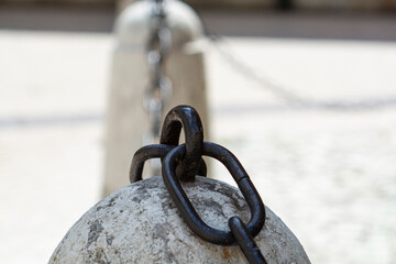 A thick heavy metal chain anchored on an Ancient stone limestone bollard next to St. Mary's...