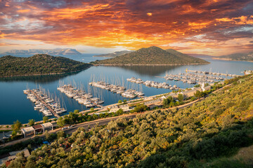 Fototapeta premium Yacht Marina. Top view aerial footage of many luxury boats and yachts in the harbor. Morning sunrise from behind the clouds. Mediterranean, Kaş, Antalya – TURKEY