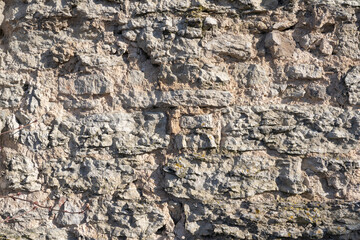 Fragment of an old dilapidated fortress wall. Limestone stone blocks cracked and partially collapsed. Background. Texture.