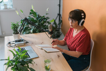 Middle-aged female radio presenter talking into the microphone and reading news - radio broadcast...